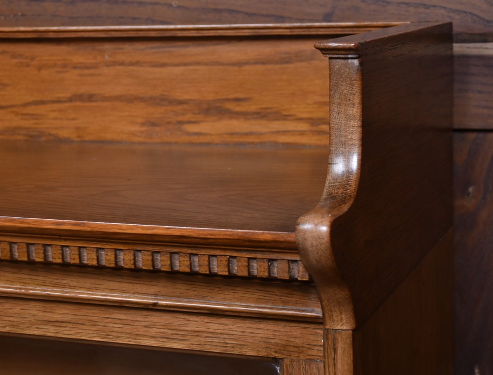 A three-tier Edwardian oak sectional bookcase featuring glass up-and-over doors with small brass knobs and a galleried top. View IV