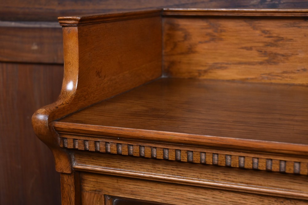 A three-tier Edwardian oak sectional bookcase featuring glass up-and-over doors with small brass knobs and a galleried top. View V