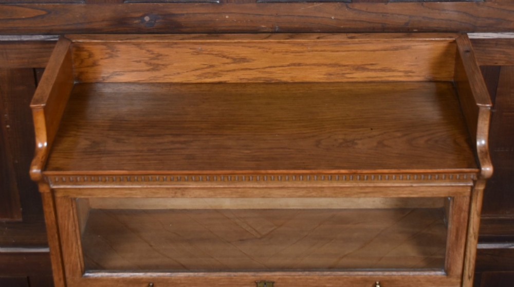 A three-tier Edwardian oak sectional bookcase featuring glass up-and-over doors with small brass knobs and a galleried top. View VI