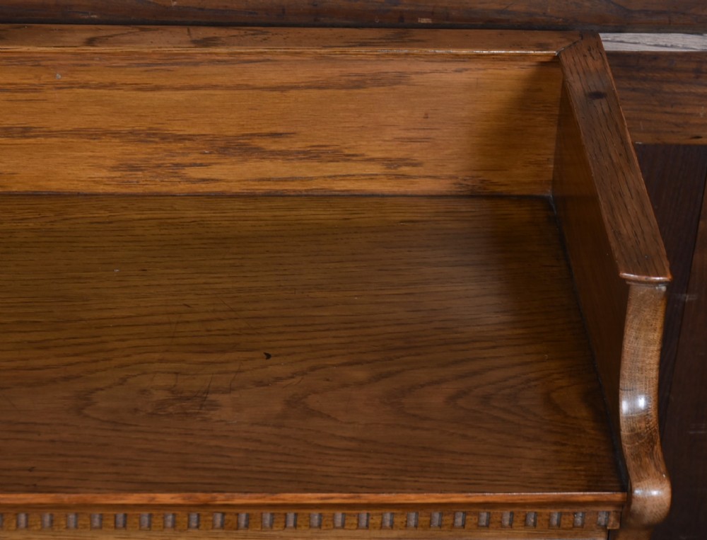 A three-tier Edwardian oak sectional bookcase featuring glass up-and-over doors with small brass knobs and a galleried top. View VIII