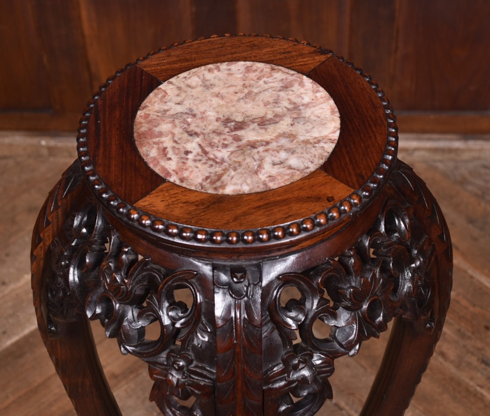 A tall dark hardwood Chinese plant stand featuring a round inset marble top, intricately carved floral aprons, and long swept legs joined by a lower central stretcher. View IV