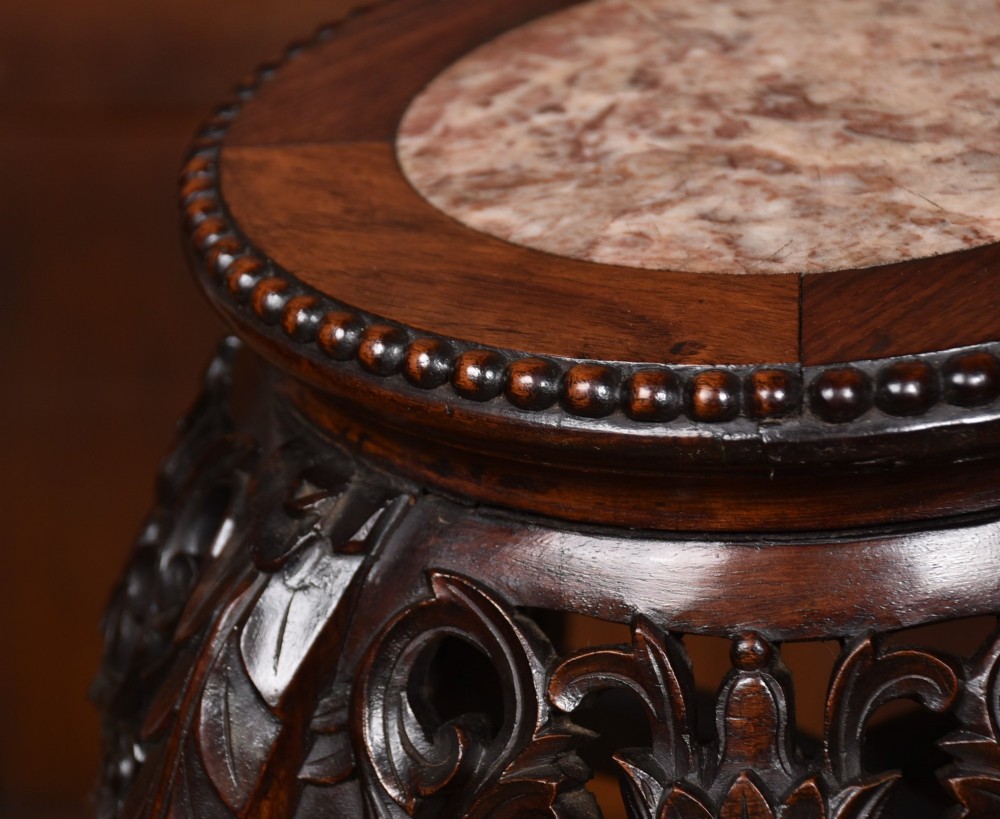 A tall dark hardwood Chinese plant stand featuring a round inset marble top, intricately carved floral aprons, and long swept legs joined by a lower central stretcher. View VII