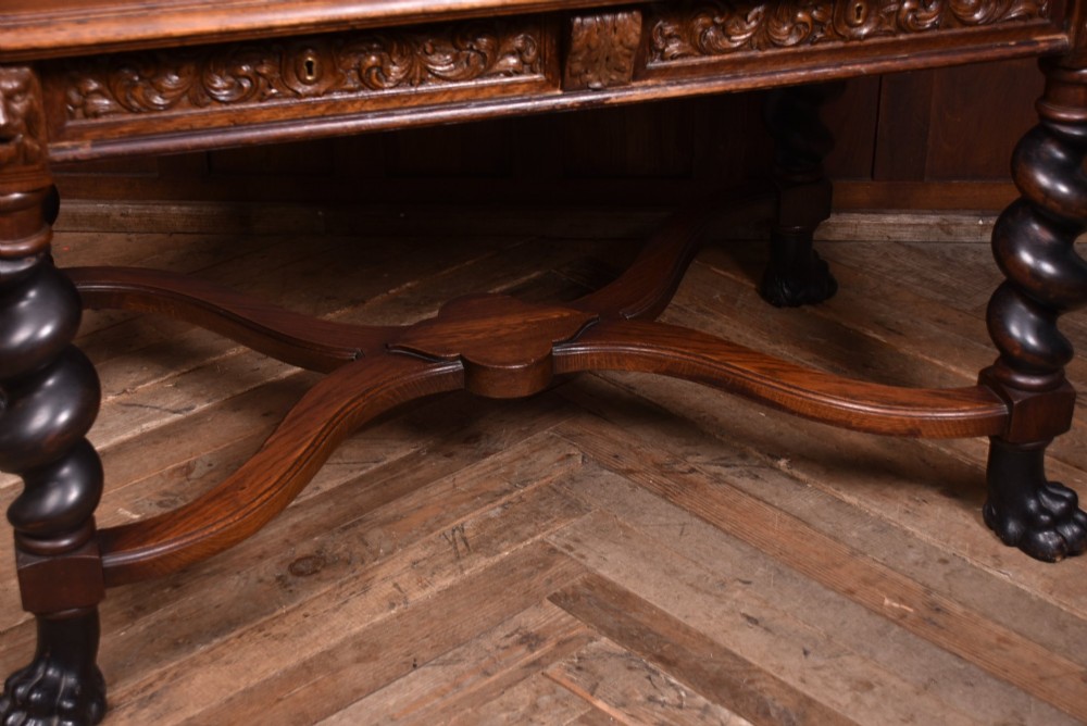 A 19th-century dark oak library table featuring barley twist legs, carved lion mask corners, an intricate apron, and an X-frame stretcher resting on paw feet. View III