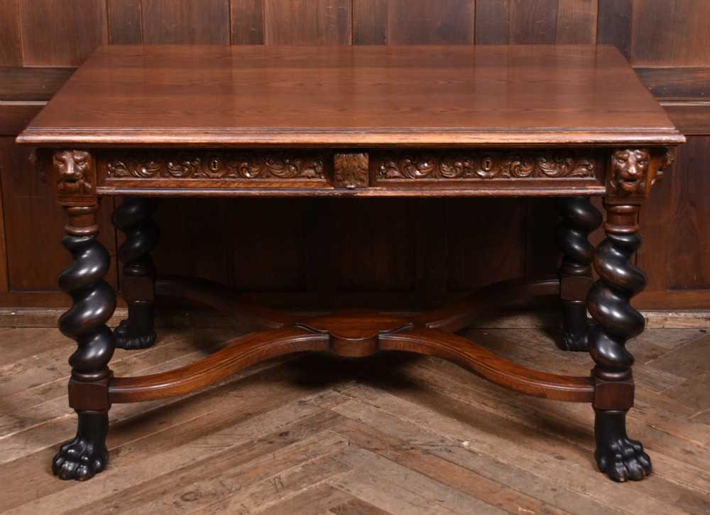 A 19th-century dark oak library table featuring barley twist legs, carved lion mask corners, an intricate apron, and an X-frame stretcher resting on paw feet. View IV