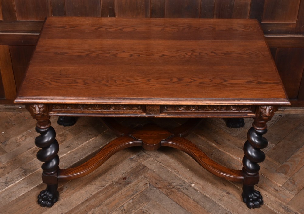 A 19th-century dark oak library table featuring barley twist legs, carved lion mask corners, an intricate apron, and an X-frame stretcher resting on paw feet. View V