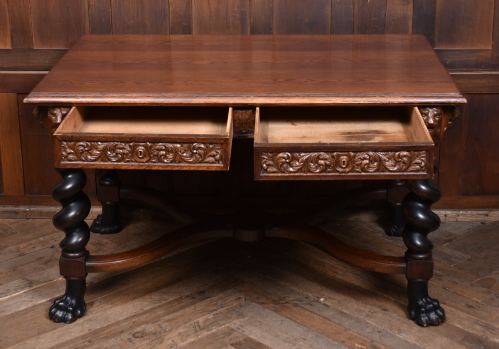 A 19th-century dark oak library table featuring barley twist legs, carved lion mask corners, an intricate apron, and an X-frame stretcher resting on paw feet. View VI