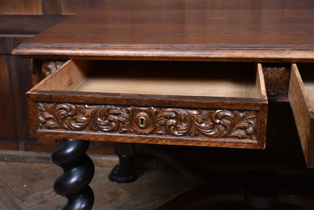 A 19th-century dark oak library table featuring barley twist legs, carved lion mask corners, an intricate apron, and an X-frame stretcher resting on paw feet. View VII