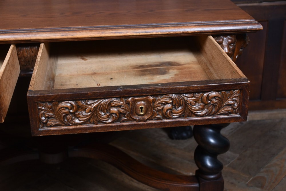 A 19th-century dark oak library table featuring barley twist legs, carved lion mask corners, an intricate apron, and an X-frame stretcher resting on paw feet. View VIII