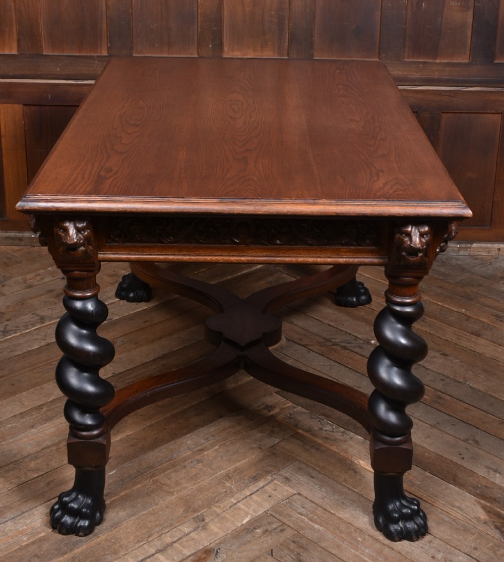 A 19th-century dark oak library table featuring barley twist legs, carved lion mask corners, an intricate apron, and an X-frame stretcher resting on paw feet. View IX