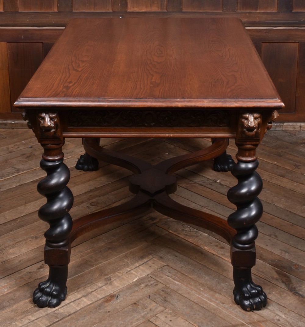 A 19th-century dark oak library table featuring barley twist legs, carved lion mask corners, an intricate apron, and an X-frame stretcher resting on paw feet. View XI