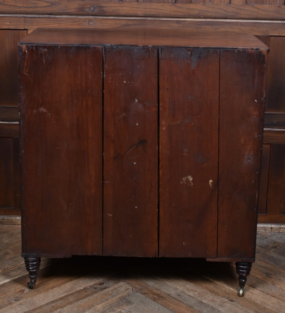 An early nineteenth-century mahogany bow-front chest of drawers featuring five graduated drawers with oval brass handles and turned feet. View IX