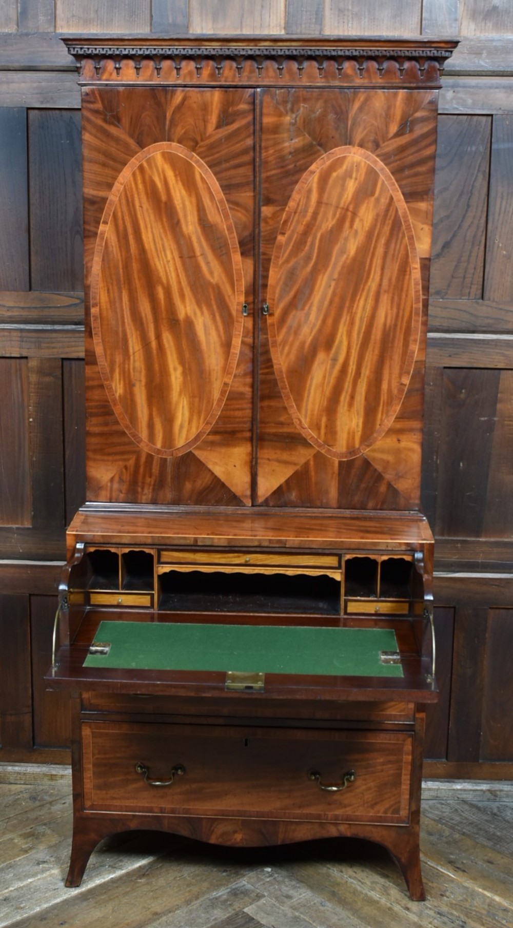 A tall Georgian mahogany secretaire bookcase featuring an upper two-door cabinet with oval inlay panels above a lower chest with four drawers and brass swan-neck handles. View II