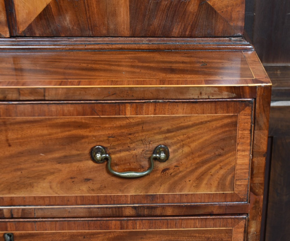 A tall Georgian mahogany secretaire bookcase featuring an upper two-door cabinet with oval inlay panels above a lower chest with four drawers and brass swan-neck handles. View VIII