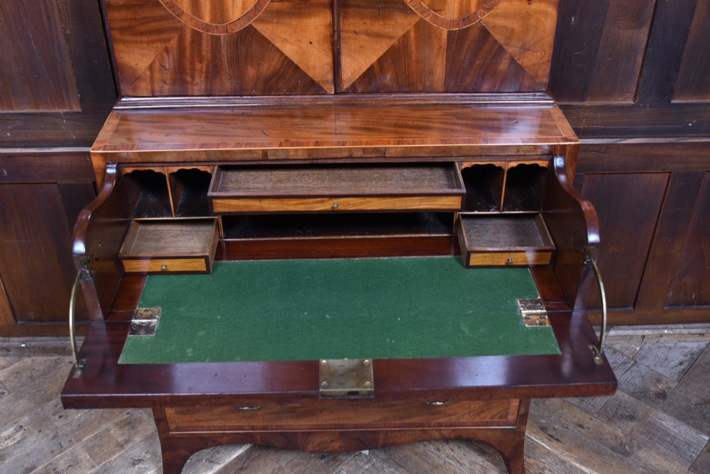 A tall Georgian mahogany secretaire bookcase featuring an upper two-door cabinet with oval inlay panels above a lower chest with four drawers and brass swan-neck handles. View XII