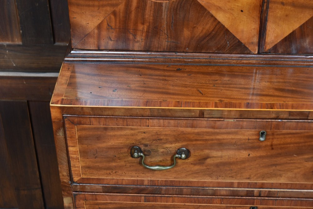 A tall Georgian mahogany secretaire bookcase featuring an upper two-door cabinet with oval inlay panels above a lower chest with four drawers and brass swan-neck handles. View XV