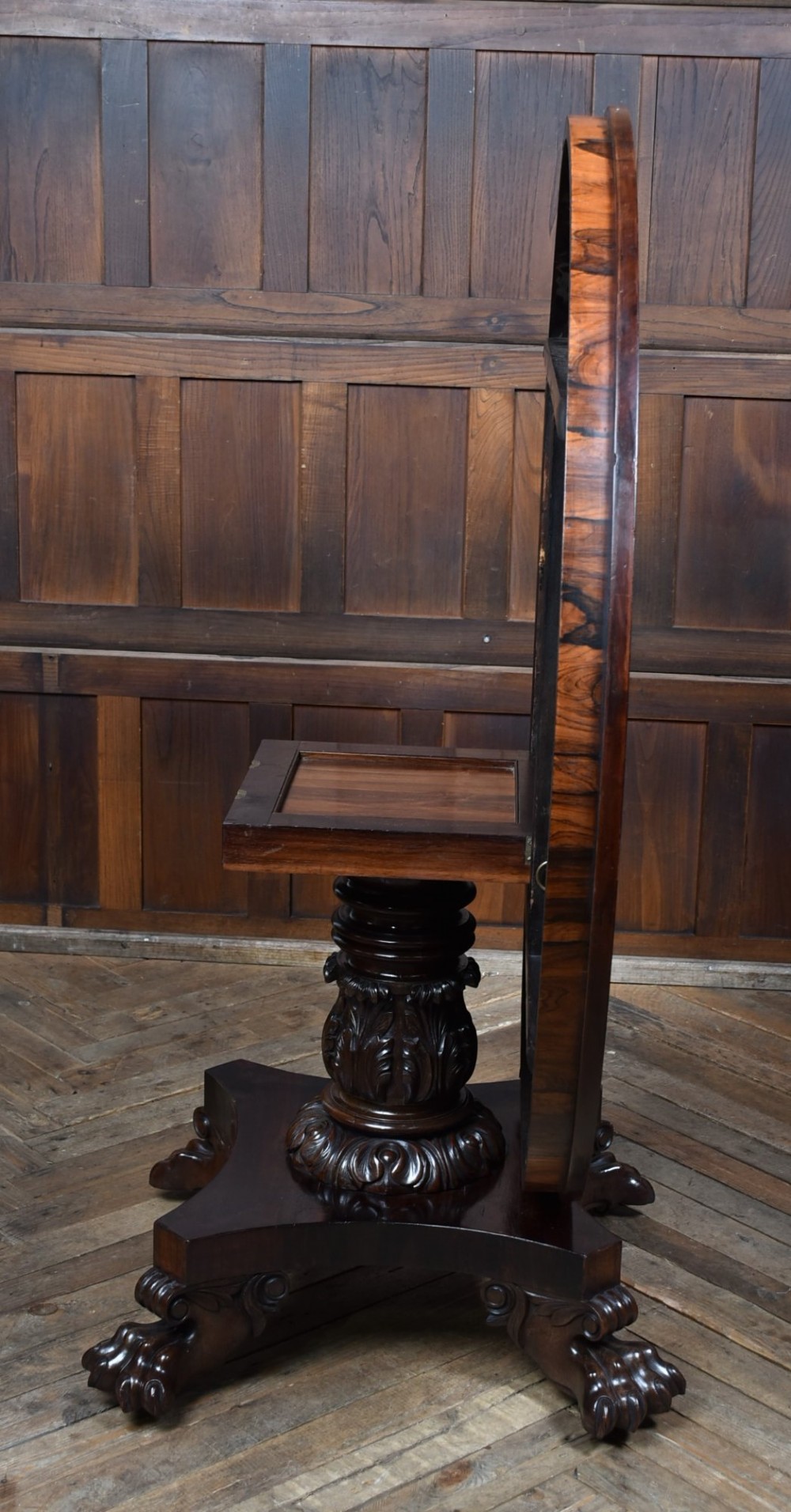 A circular Victorian rosewood tilt-top table featuring highly figured timber grain, a deep apron, a carved central pedestal column, and a quadform base on carved claw feet. View VIII