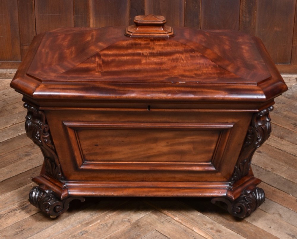 A Victorian mahogany sarcophagus-shaped cellarette featuring carved corner pilasters, a stepped hinged lid, and carved scroll feet. View II