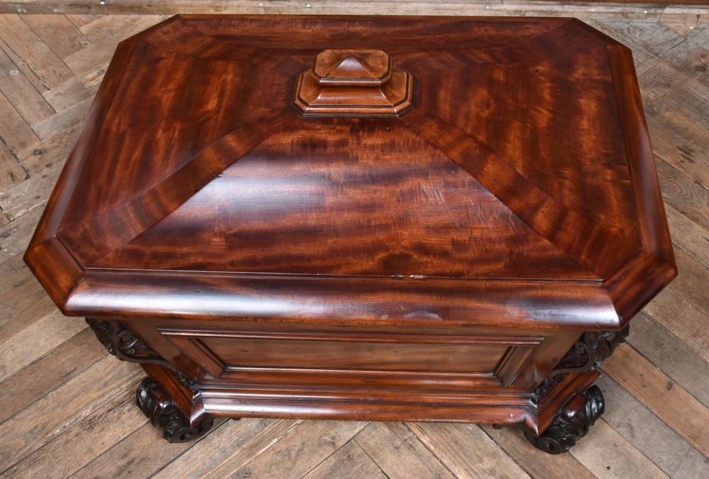 A Victorian mahogany sarcophagus-shaped cellarette featuring carved corner pilasters, a stepped hinged lid, and carved scroll feet. View IV