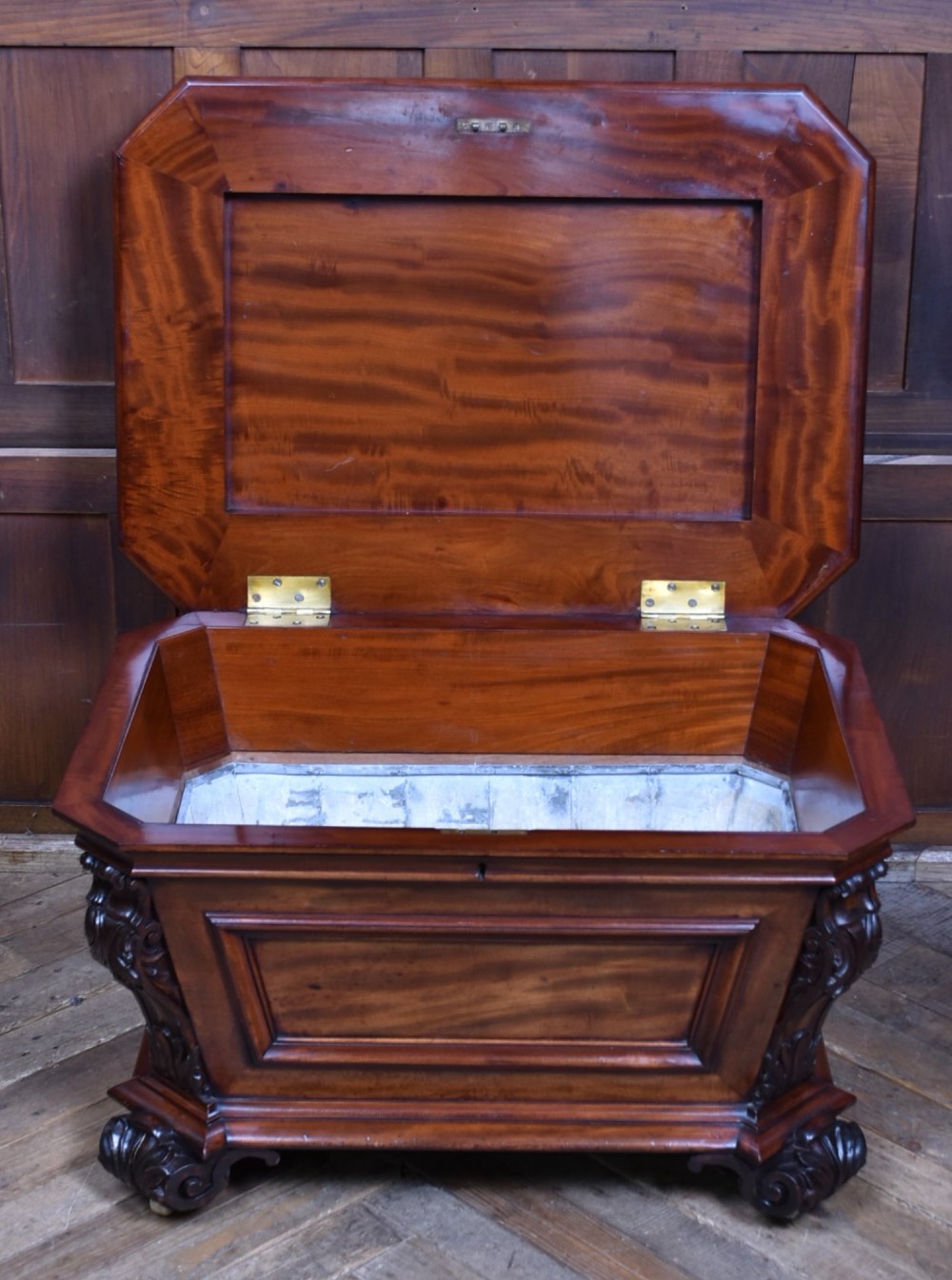 A Victorian mahogany sarcophagus-shaped cellarette featuring carved corner pilasters, a stepped hinged lid, and carved scroll feet. View VI
