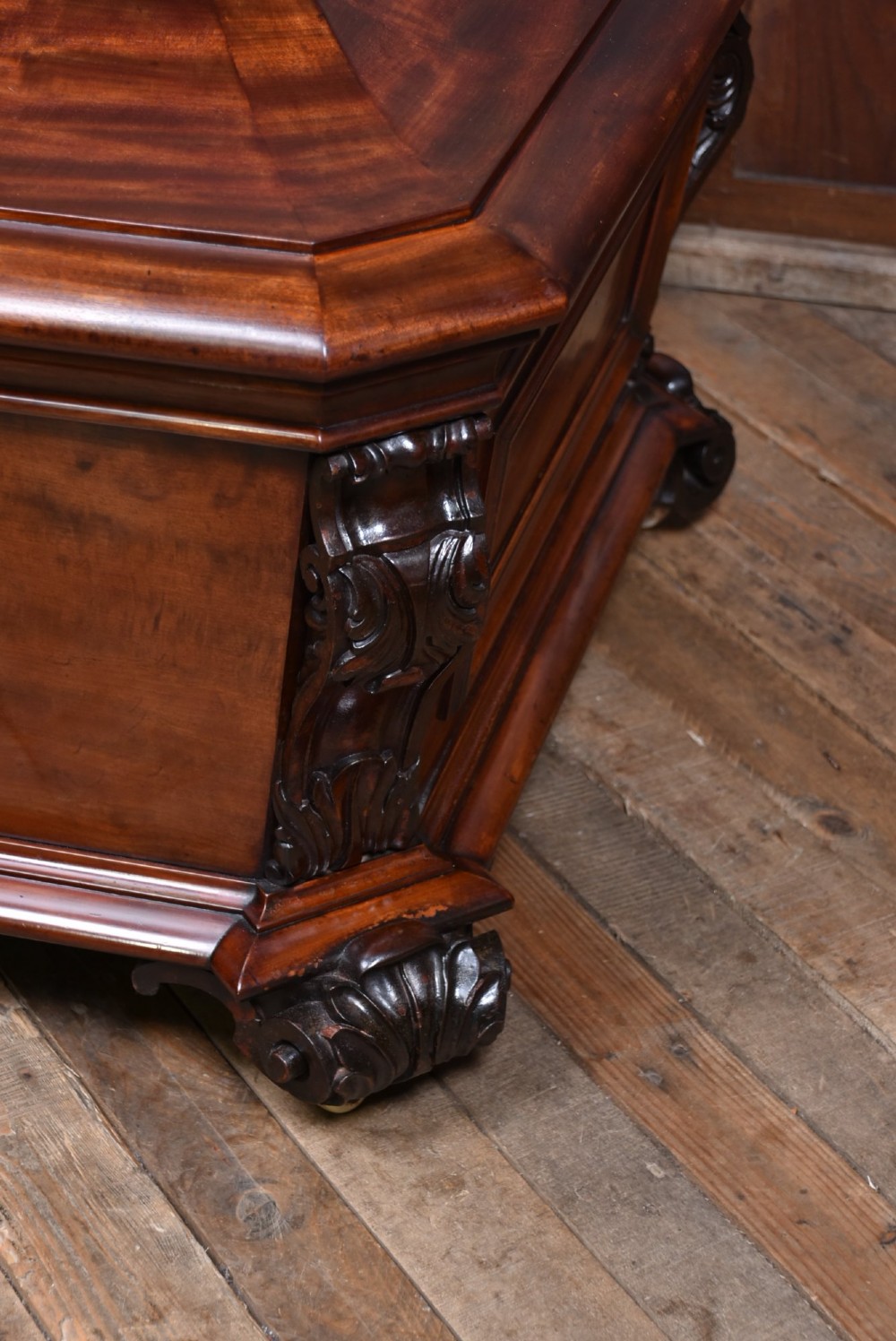 A Victorian mahogany sarcophagus-shaped cellarette featuring carved corner pilasters, a stepped hinged lid, and carved scroll feet. View IX