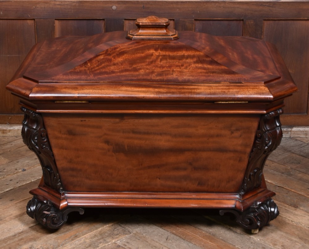 A Victorian mahogany sarcophagus-shaped cellarette featuring carved corner pilasters, a stepped hinged lid, and carved scroll feet. View X