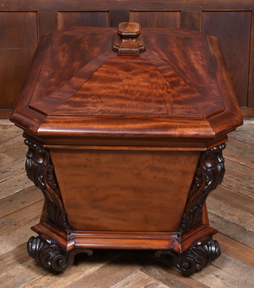 A Victorian mahogany sarcophagus-shaped cellarette featuring carved corner pilasters, a stepped hinged lid, and carved scroll feet. View XI