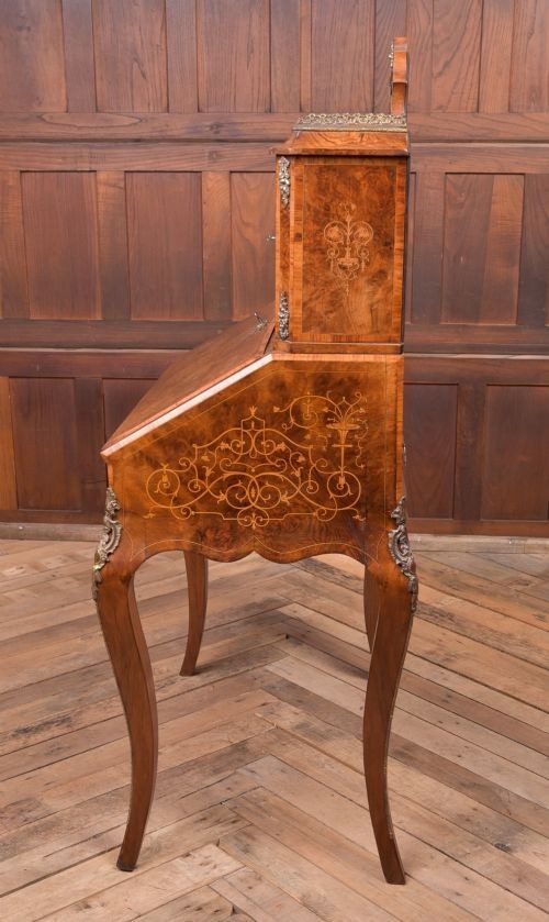 An antique French walnut ladys writing desk featuring floral marquetry, cabriole legs, brass mounts, and a raised upper section with glass cabinets and a central mirror. View XI