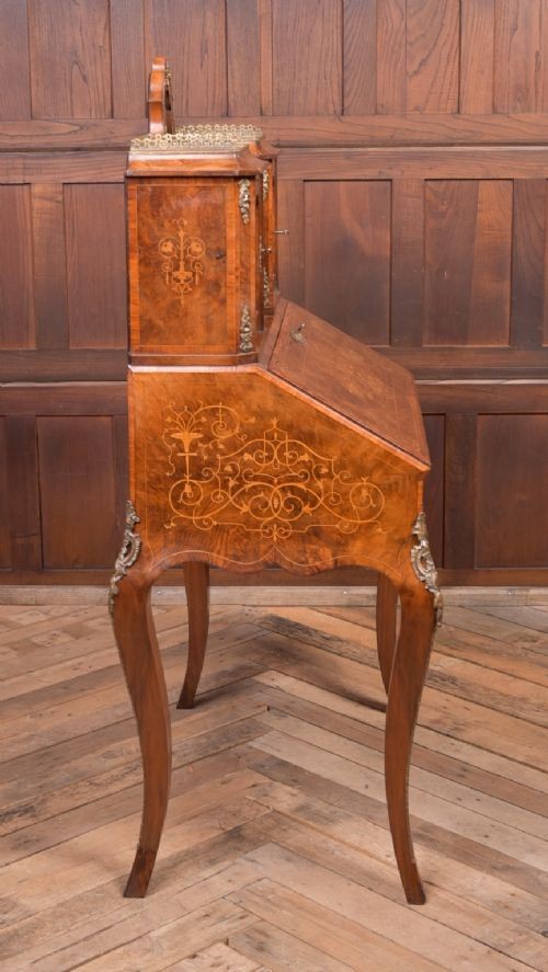 An antique French walnut ladys writing desk featuring floral marquetry, cabriole legs, brass mounts, and a raised upper section with glass cabinets and a central mirror. View XIV