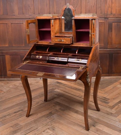 An antique French walnut ladys writing desk featuring floral marquetry, cabriole legs, brass mounts, and a raised upper section with glass cabinets and a central mirror. View XV