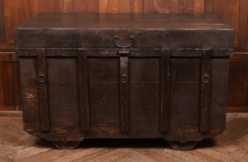 A dark brown Japanese wooden storage chest set on small wheels with vertical timber battens and hand-forged iron fittings.
