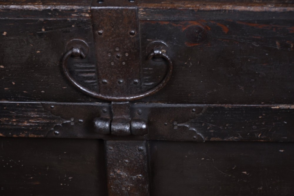 A dark brown Japanese wooden storage chest set on small wheels with vertical timber battens and hand-forged iron fittings. View II