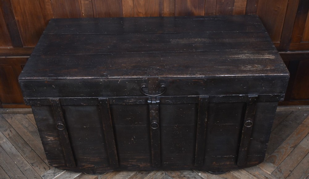 A dark brown Japanese wooden storage chest set on small wheels with vertical timber battens and hand-forged iron fittings. View VI