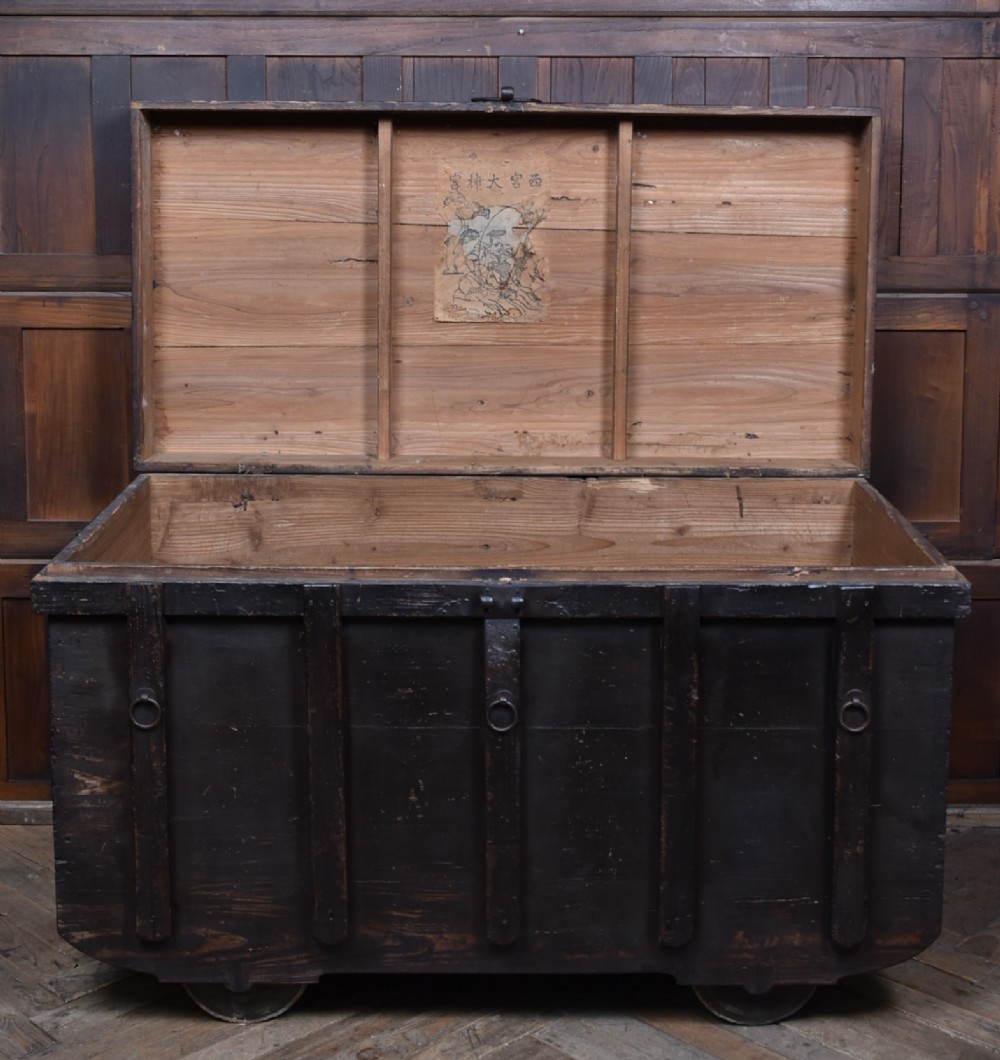 A dark brown Japanese wooden storage chest set on small wheels with vertical timber battens and hand-forged iron fittings. View VII
