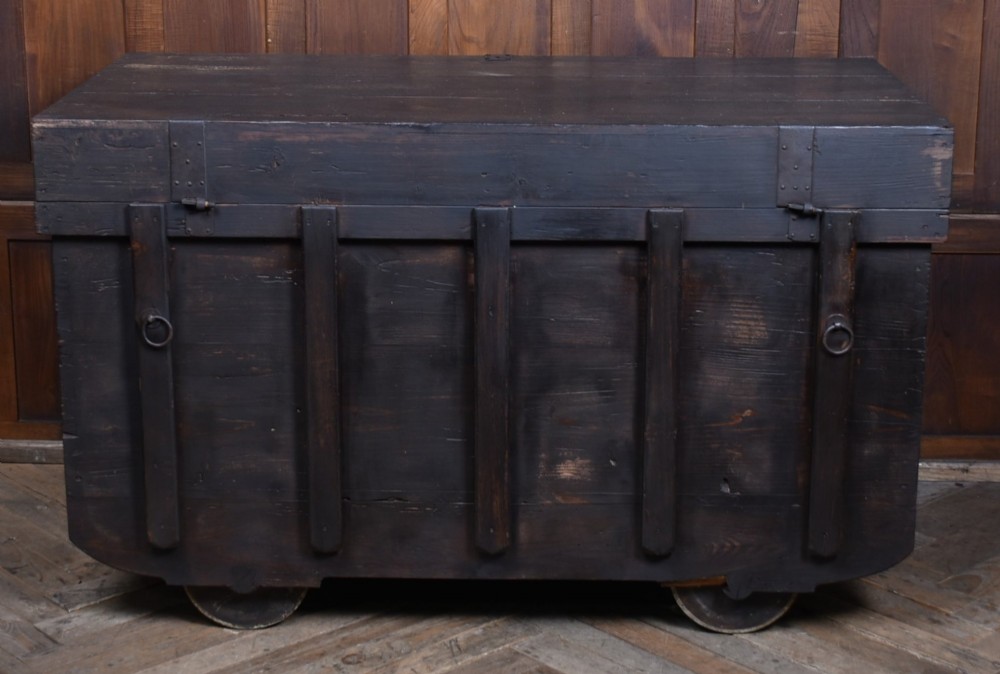 A dark brown Japanese wooden storage chest set on small wheels with vertical timber battens and hand-forged iron fittings. View XI