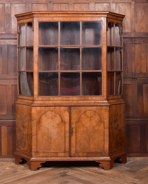 A nineteenth-century Dutch walnut display cabinet featuring a glazed upper section with individual glass panes and a lower cupboard with arched panelled doors resting on bracket feet.