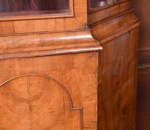 A nineteenth-century Dutch walnut display cabinet featuring a glazed upper section with individual glass panes and a lower cupboard with arched panelled doors resting on bracket feet. View XII