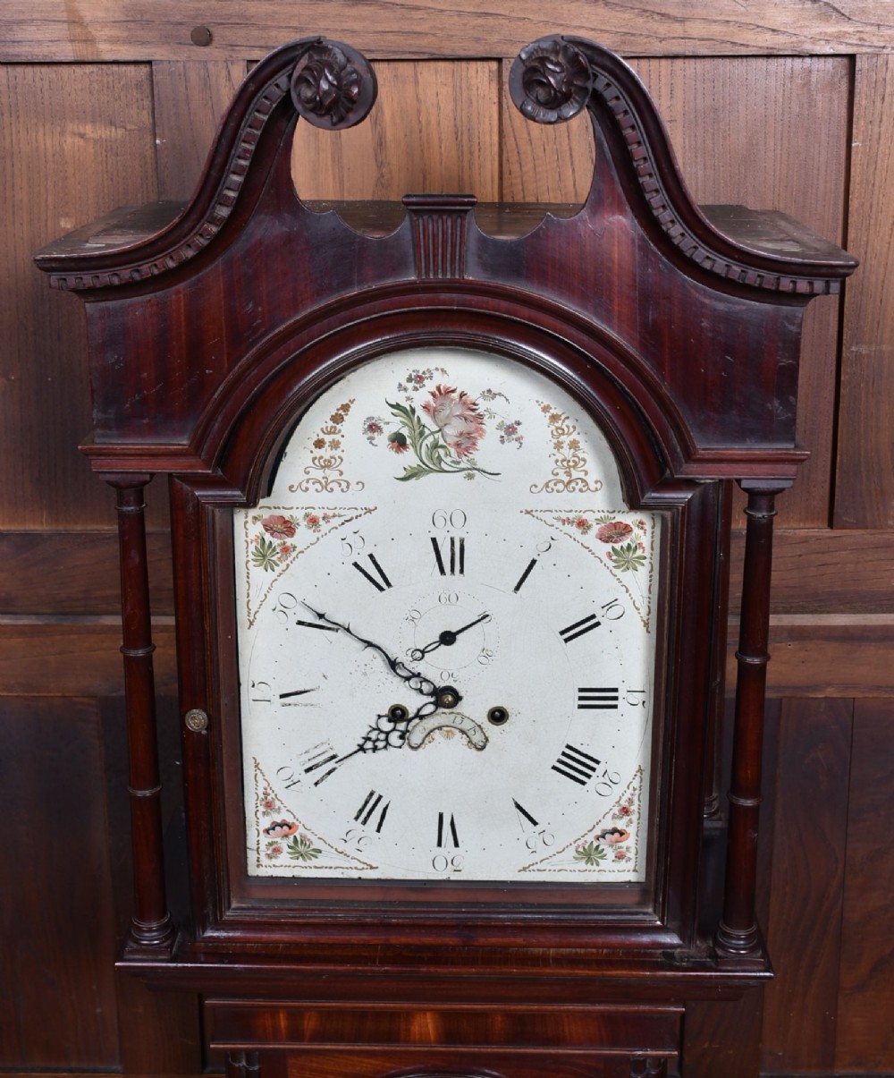 Victorian flame mahogany longcase clock featuring a swan-neck pediment, arched painted dial with floral spandrels, and a tall veneered trunk door. View II