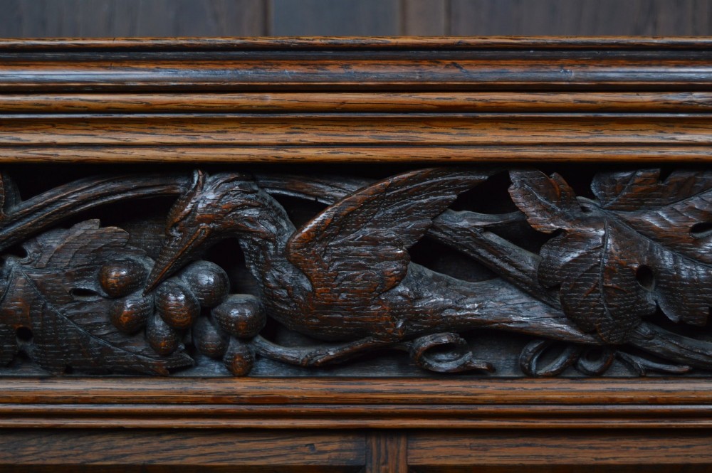 A wide 19th-century Victorian Gothic Revival open oak bookcase featuring detailed floral carvings, moulded pilasters, and twin bays of adjustable wooden shelves. View III