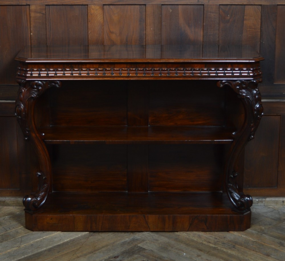 A dark Victorian rosewood console table featuring carved S-scroll supports, an open central shelf, a beaded upper frieze, and a solid plinth base. View II