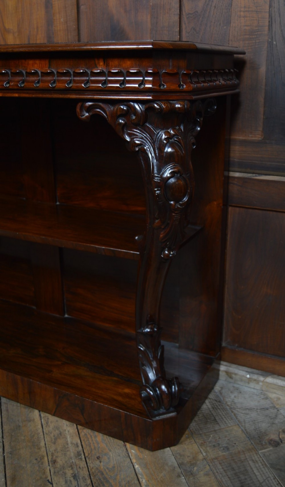 A dark Victorian rosewood console table featuring carved S-scroll supports, an open central shelf, a beaded upper frieze, and a solid plinth base. View III