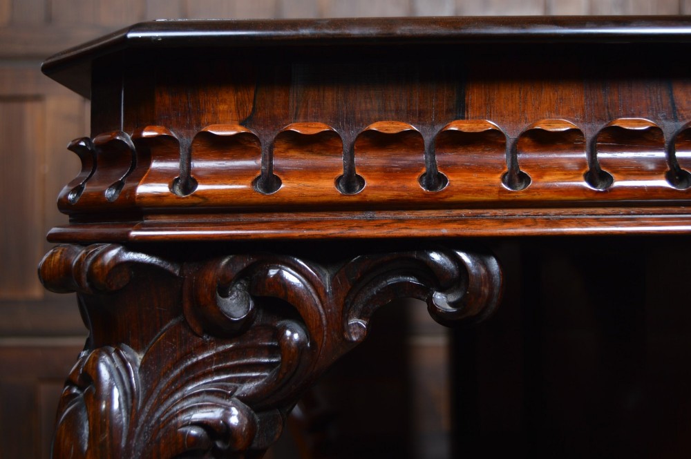A dark Victorian rosewood console table featuring carved S-scroll supports, an open central shelf, a beaded upper frieze, and a solid plinth base. View XII