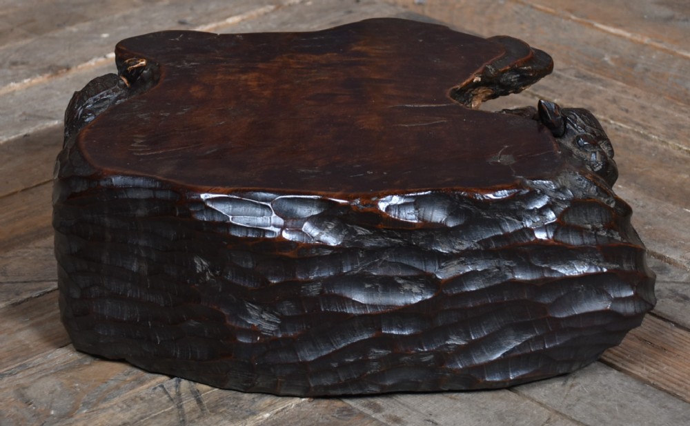 A dark brown carved hardwood display stand featuring a hand-carved turtle motif along the organic natural edge. View VII