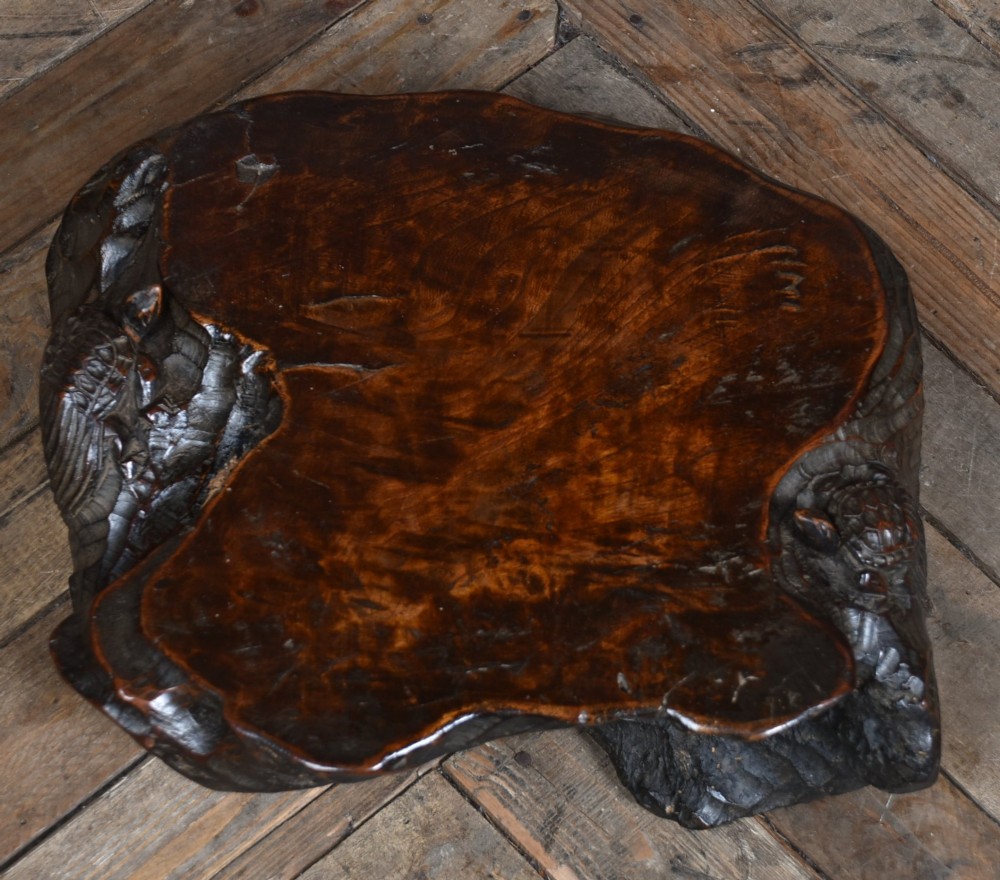 A dark brown carved hardwood display stand featuring a hand-carved turtle motif along the organic natural edge. View X