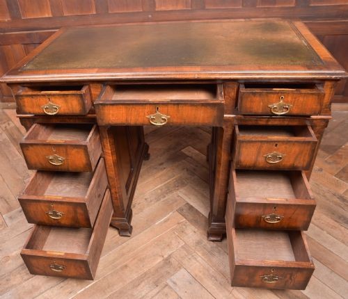 An Edwardian walnut pedestal desk featuring nine drawers with brass swan-neck handles, panelled sides, and bracket feet. View VIII