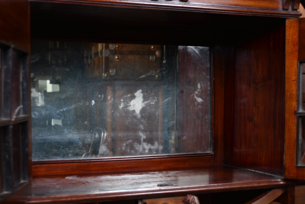 An Art Nouveau dark mahogany display cabinet featuring botanical inlay motifs, glazed upper doors, a central mirrored recess, a single drawer, and curved side brackets. View V