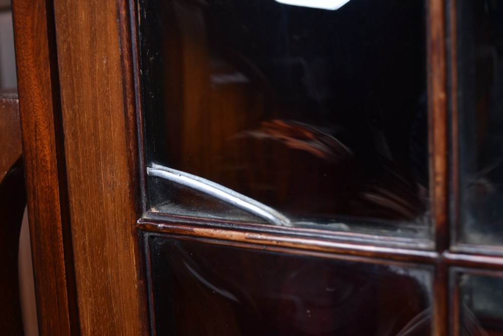 An Art Nouveau dark mahogany display cabinet featuring botanical inlay motifs, glazed upper doors, a central mirrored recess, a single drawer, and curved side brackets. View VI