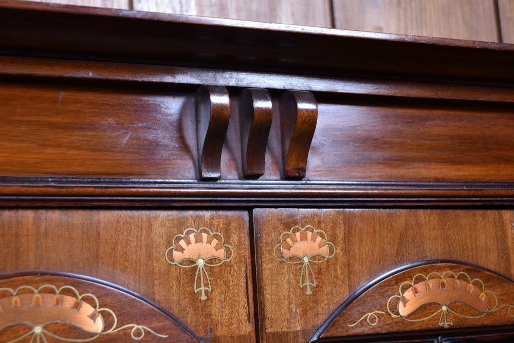An Art Nouveau dark mahogany display cabinet featuring botanical inlay motifs, glazed upper doors, a central mirrored recess, a single drawer, and curved side brackets. View VII