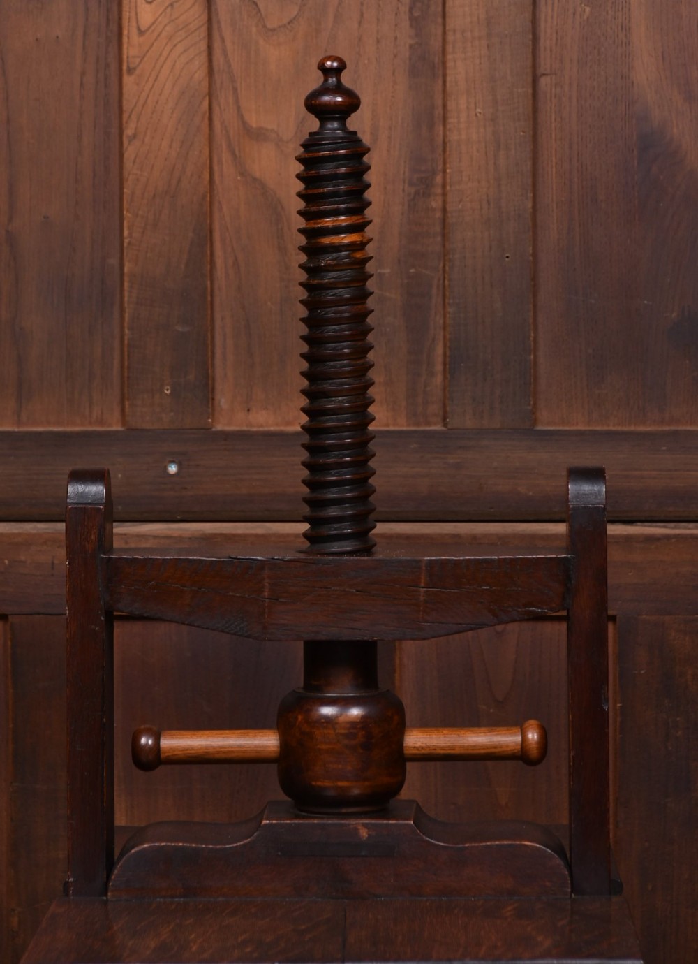 A Victorian dark oak wooden book press featuring a large central hand-turned screw mechanism and solid platen shelves. View VII