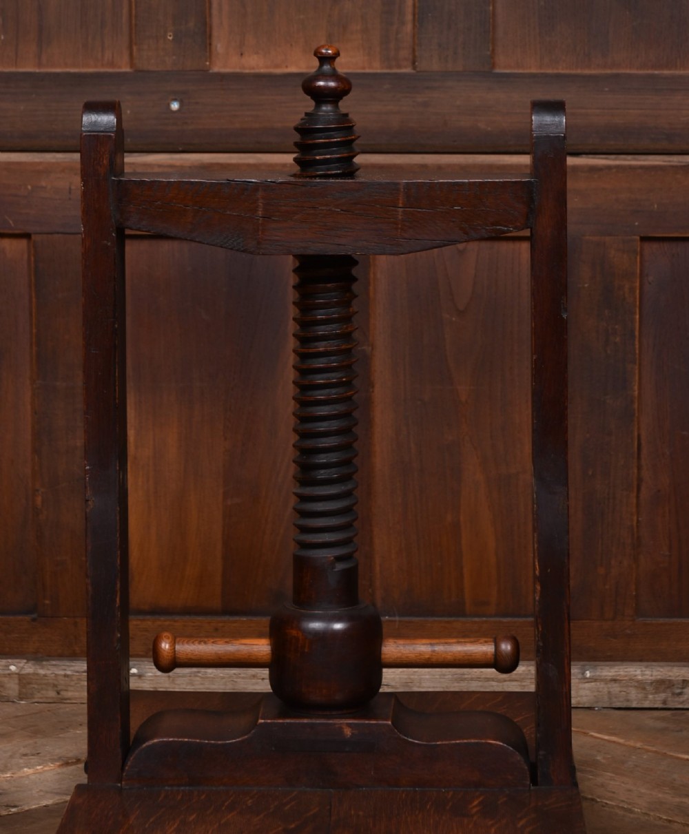 A Victorian dark oak wooden book press featuring a large central hand-turned screw mechanism and solid platen shelves. View X