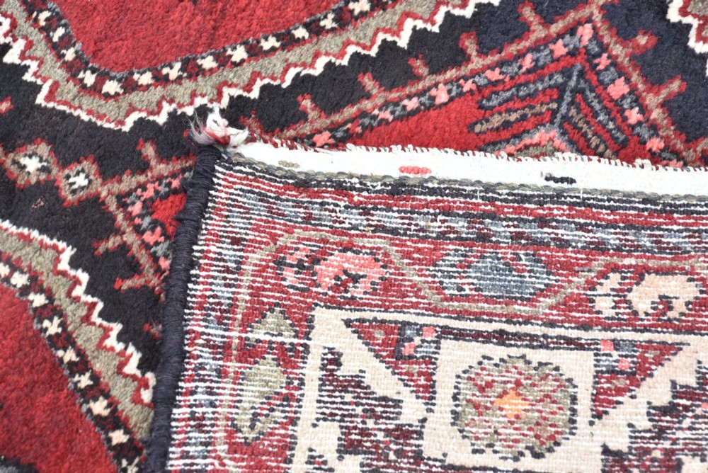 A long handwoven wool runner rug featuring five central diamond medallions on a dark red ground with geometric borders. View VI